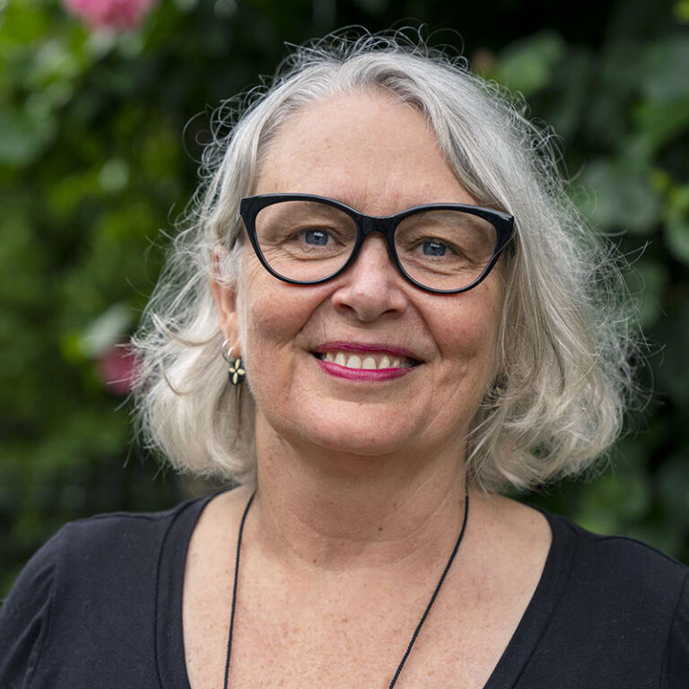 Board member and Executive Director Kathryn McPhillips biography page. A woman with shoulder length white hair and black glasses.
